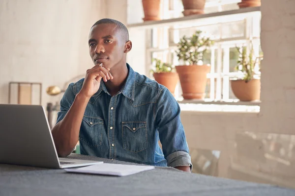 Director thinking things through at a laptop in a bright home office